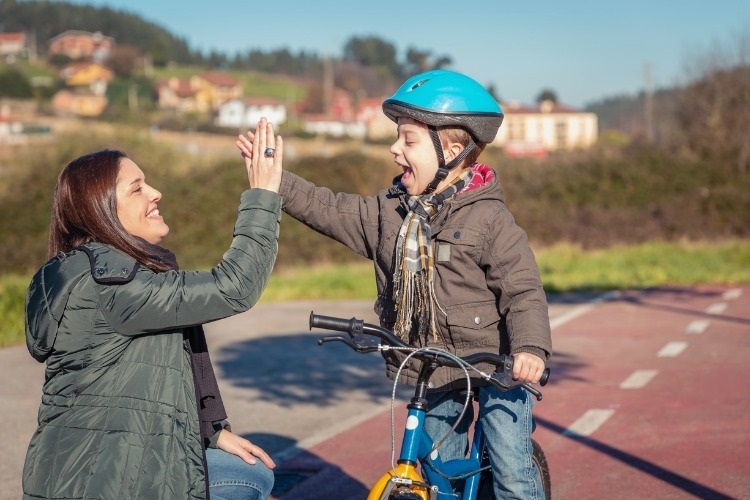 mother-and-son-giving-five-by-success-riding-bicycle-picture-id973108978