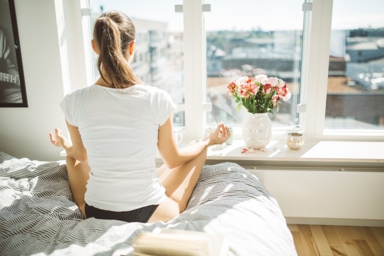 beautiful-woman-practicing-yoga-in-front-of-window-of-cozy-and-picture-id918131058