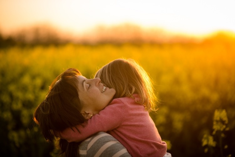 little-girl-embracing-her-mom-in-the-rapeseed-field-picture-id941817136