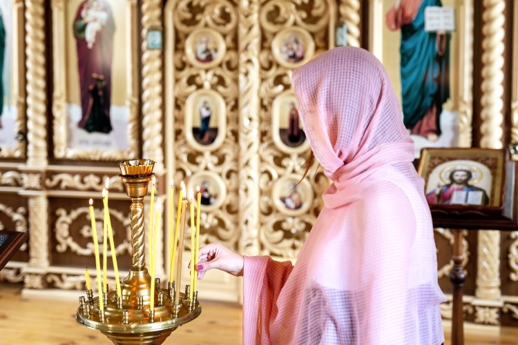young-woman-in-pink-headscarf-praying-near-candles-at-wooden-church-picture-id1013847868