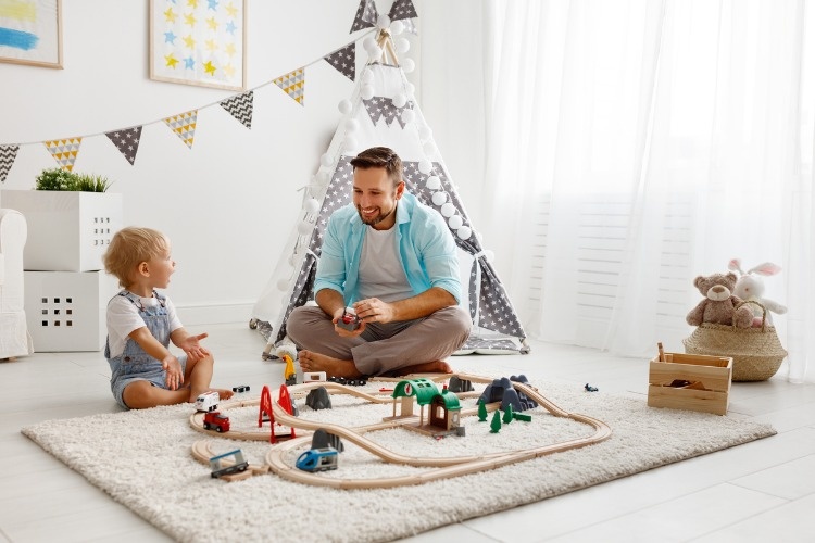 happy-family-father-and-child-son-playing-in-toy-railway-in-playroom-picture-id910871690