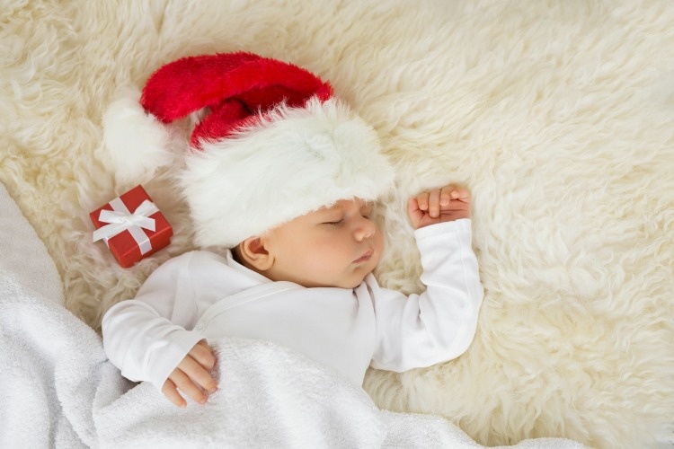 baby-sleeping-with-christmas-hat-on-and-gift-box-picture-id621382426