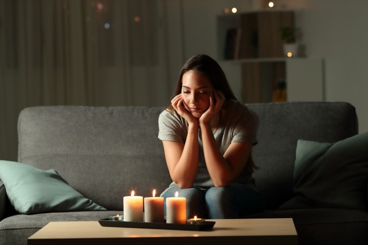 distracted-woman-looking-at-candles-light-during-blackout-picture-id1003789054_01