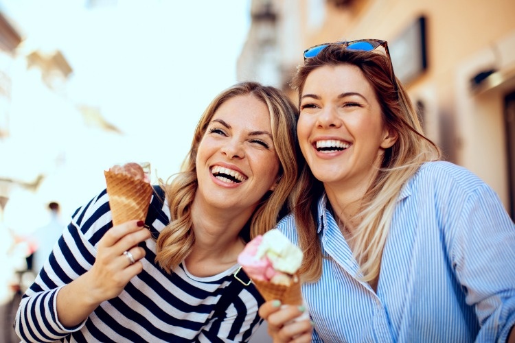 two-young-women-laughing-and-holding-ice-cream-in-hand-picture-id936618458