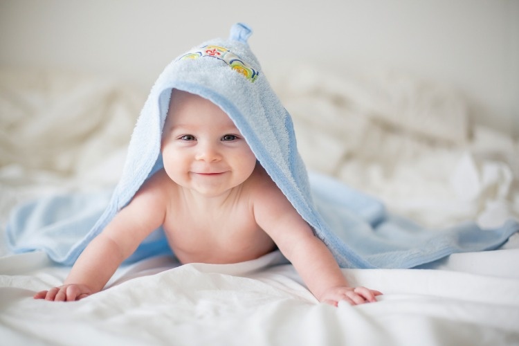 cute-little-baby-boy-relaxing-in-bed-after-bath-smiling-happily-picture-id923852236
