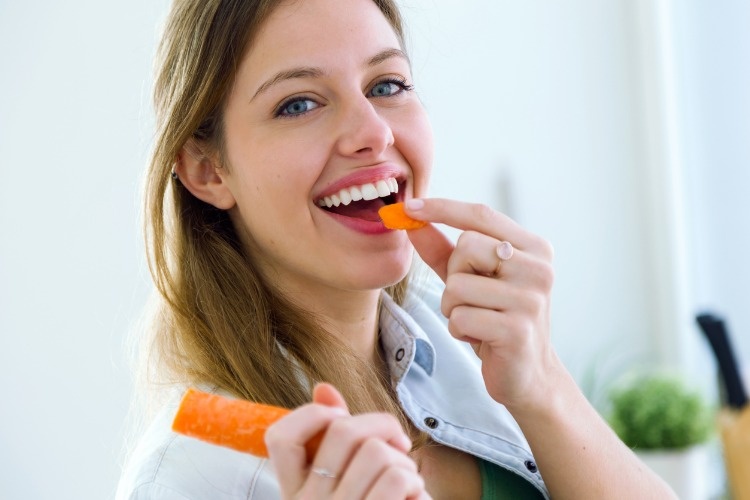 pretty-young-woman-eating-carrot-in-the-kitchen-picture-id502447580_01